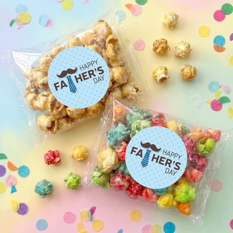 Personalized popcorn bags with blue round 'Happy Fa Her's Day' stickers, two bags on surface