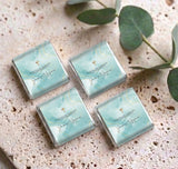 Set of mini personalized chocolate boxes with teal wrap and gold cross