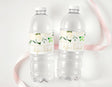 Clear plastic water bottles with white floral personalised labels and green leaves.
