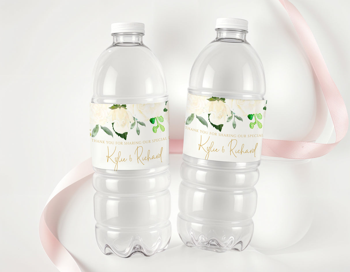 Clear plastic water bottles with white floral personalised labels and green leaves.