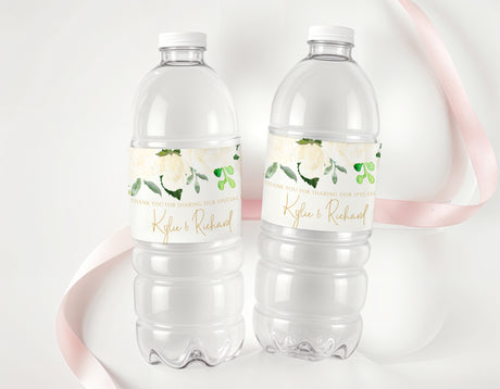 Clear plastic water bottles with white floral personalised labels and green leaves.
