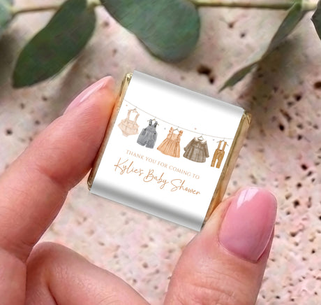 Mini chocolates in foil wrappers, held in hand with baby clothes icons