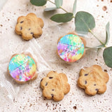 Chocolate chip cookies with tie-dye round birthday toppers, arranged with green leaf accents
