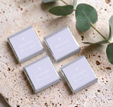 Set of four personalised mini chocolate boxes with lilac lids, white cross, and name text