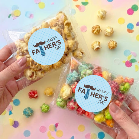 Personalized popcorn bags with blue stickers 'Happy Fa Her's Day', held in hands
