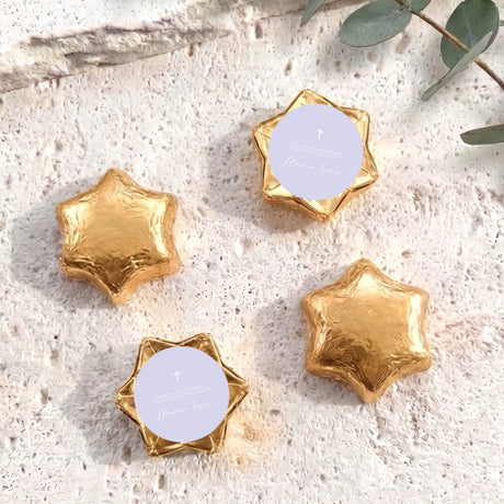 Gold foil-covered chocolate stars with white round labels and a small cross