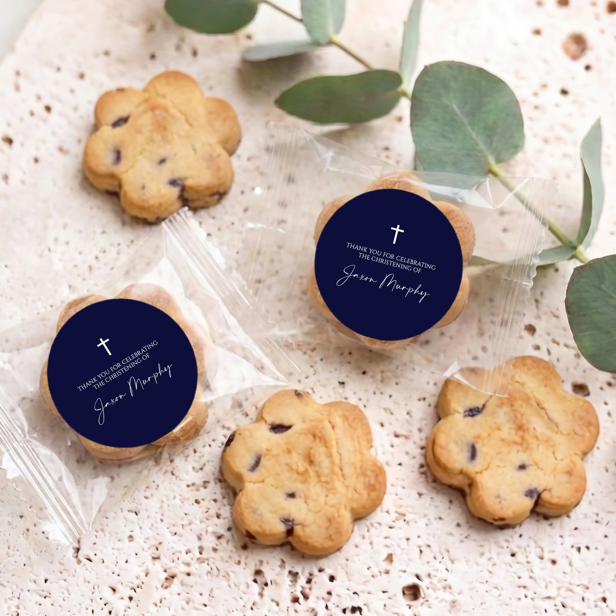 Bite-size choc chip cookies with two navy round cross labels and name on clear wraps