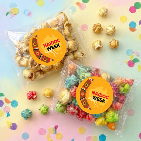 Personalised popcorn bag set with clear plastic bags of pastel popcorn and orange Naidoc Week labels