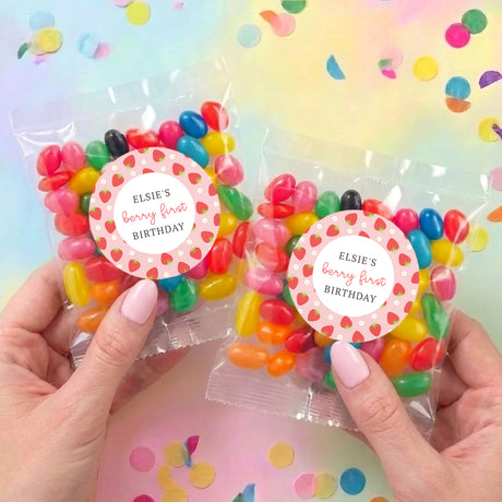 Two personalised jelly bean bags with round 'Elsie's berry first Birthday' labels held in hand