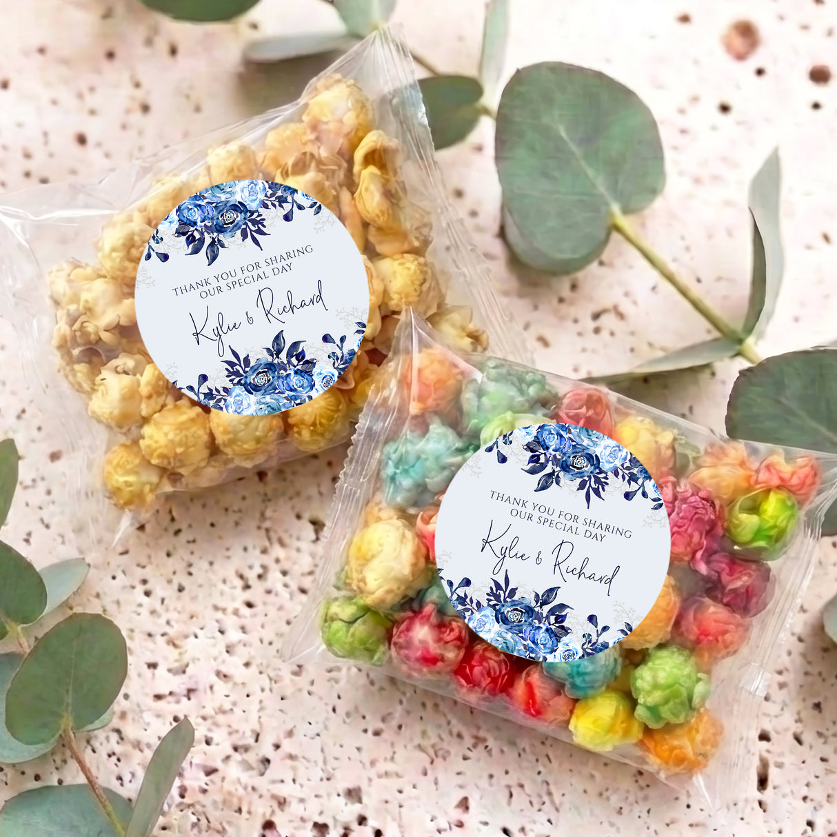 Personalised popcorn bags with clear wrappers and blue floral thank-you labels on table