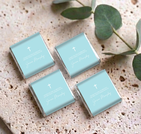 Set of pastel blue mini chocolate boxes with white cross and personalized name text