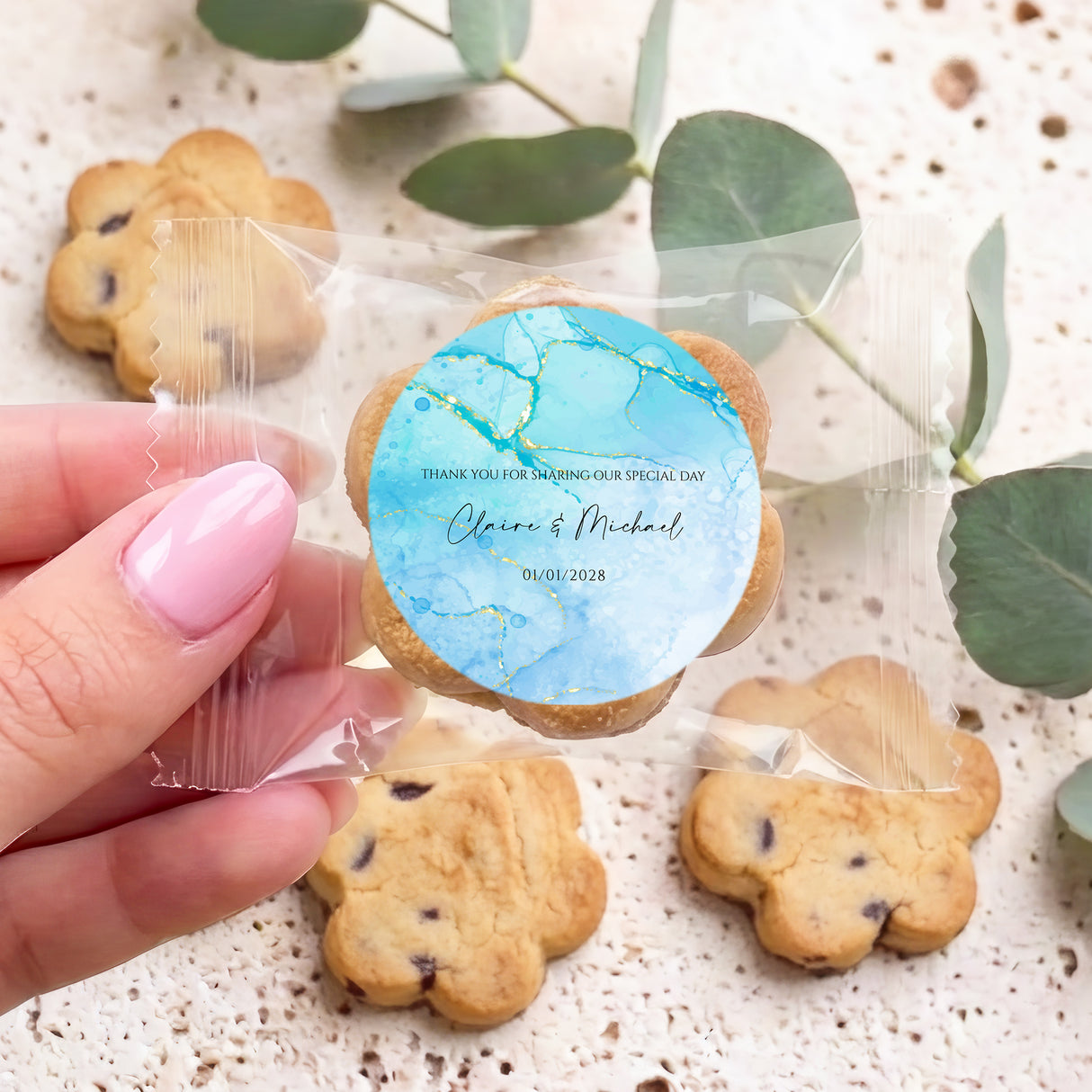 Personalised bite-size choc chip cookies with blue marble round label, held in hand