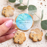 Personalised bite-size choc chip cookies with blue marble round label, held in hand