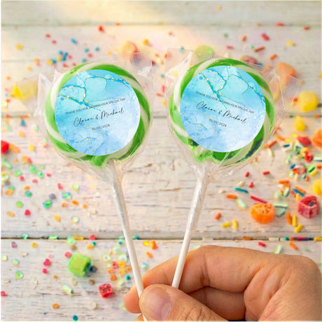 Two blue marble personalised lollipops with green rim, clear wrap on sticks