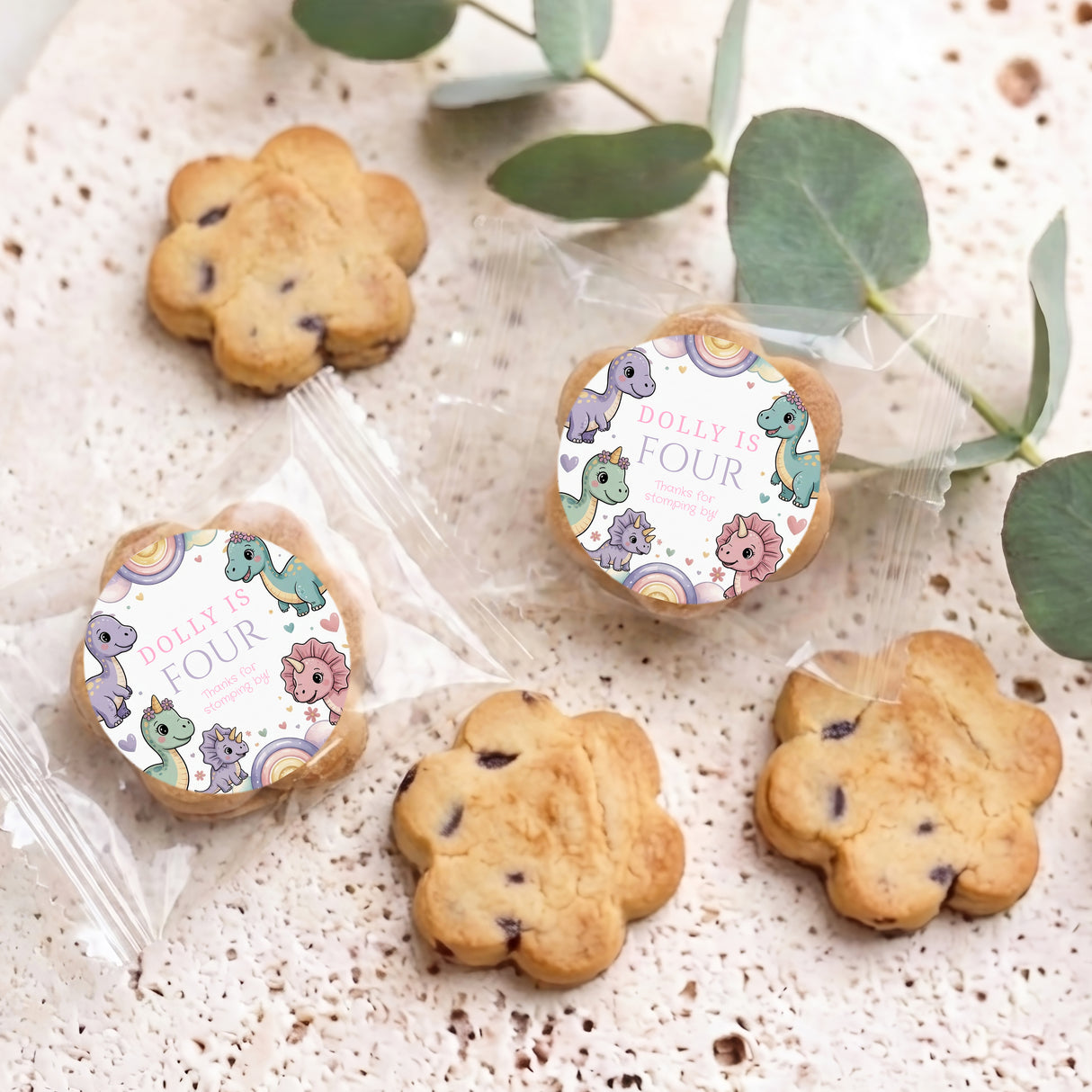 Dinosaur-themed personalized bite-size cookies with round toppers reading “Dolly is four”.
