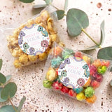 Two clear popcorn treat bags with pastel dinosaur label reading “Dolly is Four”