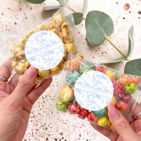 Personalised popcorn favor bag with blue round label, held in hand