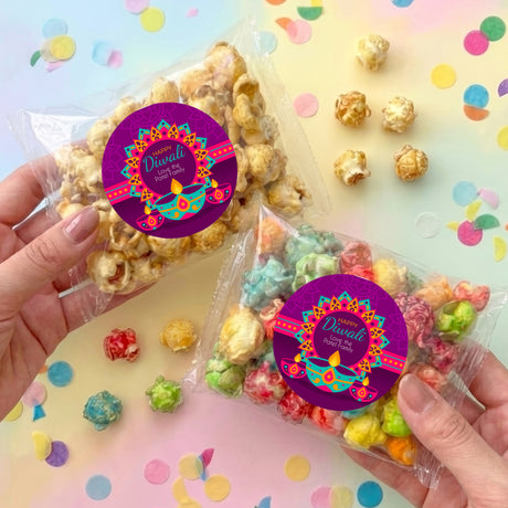 Diwali popcorn bag held in hands, clear bag with purple round label and colorful popcorn