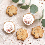 Bite-size chocolate chip cookies with two round floral thank-you stickers on clear bags