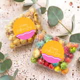 Two personalized Mother’s Day popcorn bags with multicolor popcorn in clear plastic