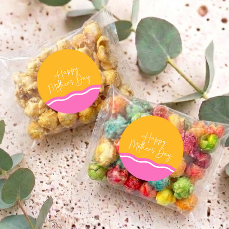 Two personalized Mother’s Day popcorn bags with multicolor popcorn in clear plastic