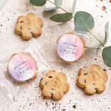 Bite-size chocolate chip cookies with round pink/purple birthday labels, on display