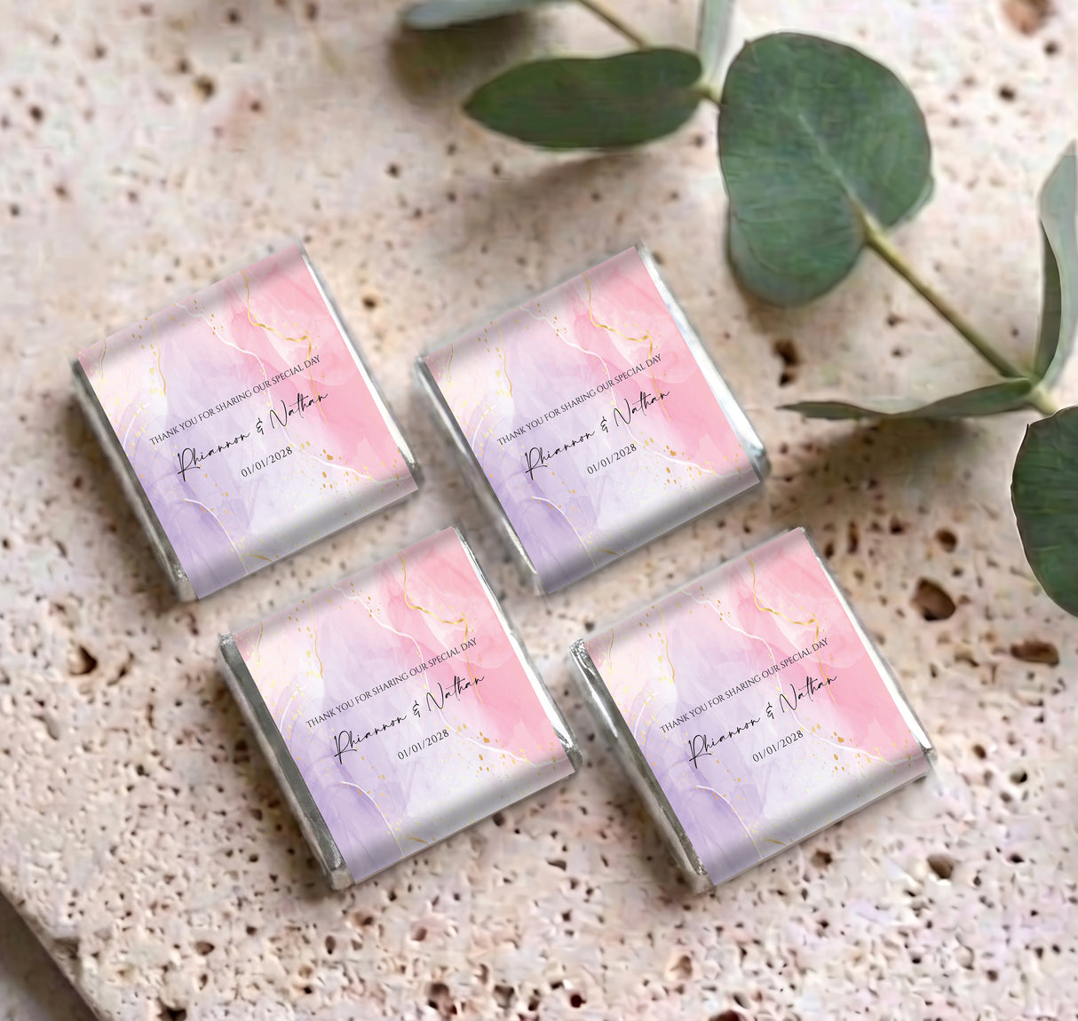 Four personalised mini chocolates with pink marble wrappers and printed names, on speckled surface