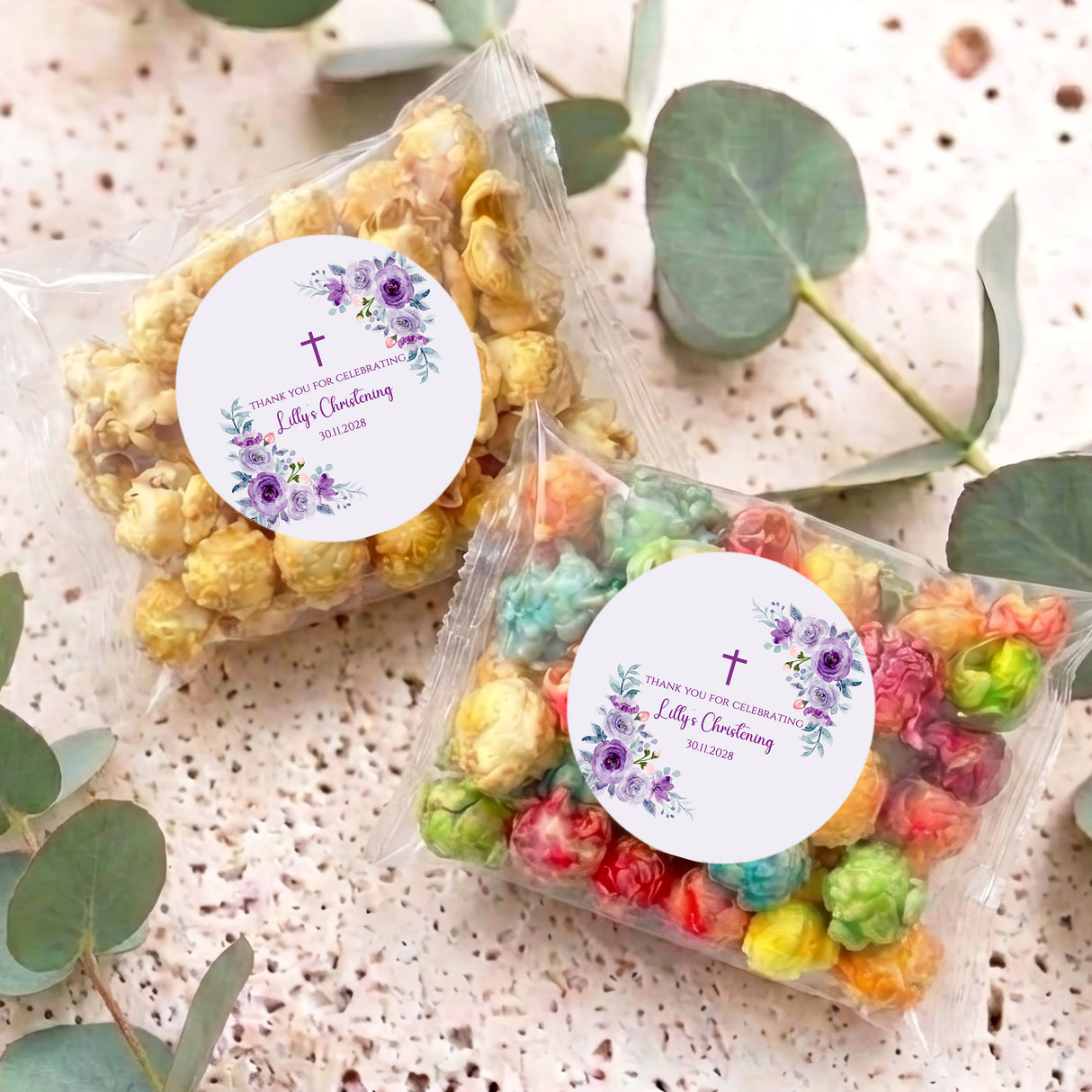 Pair of personalised popcorn bags with clear wrappers, colorful popcorn, and floral round labels