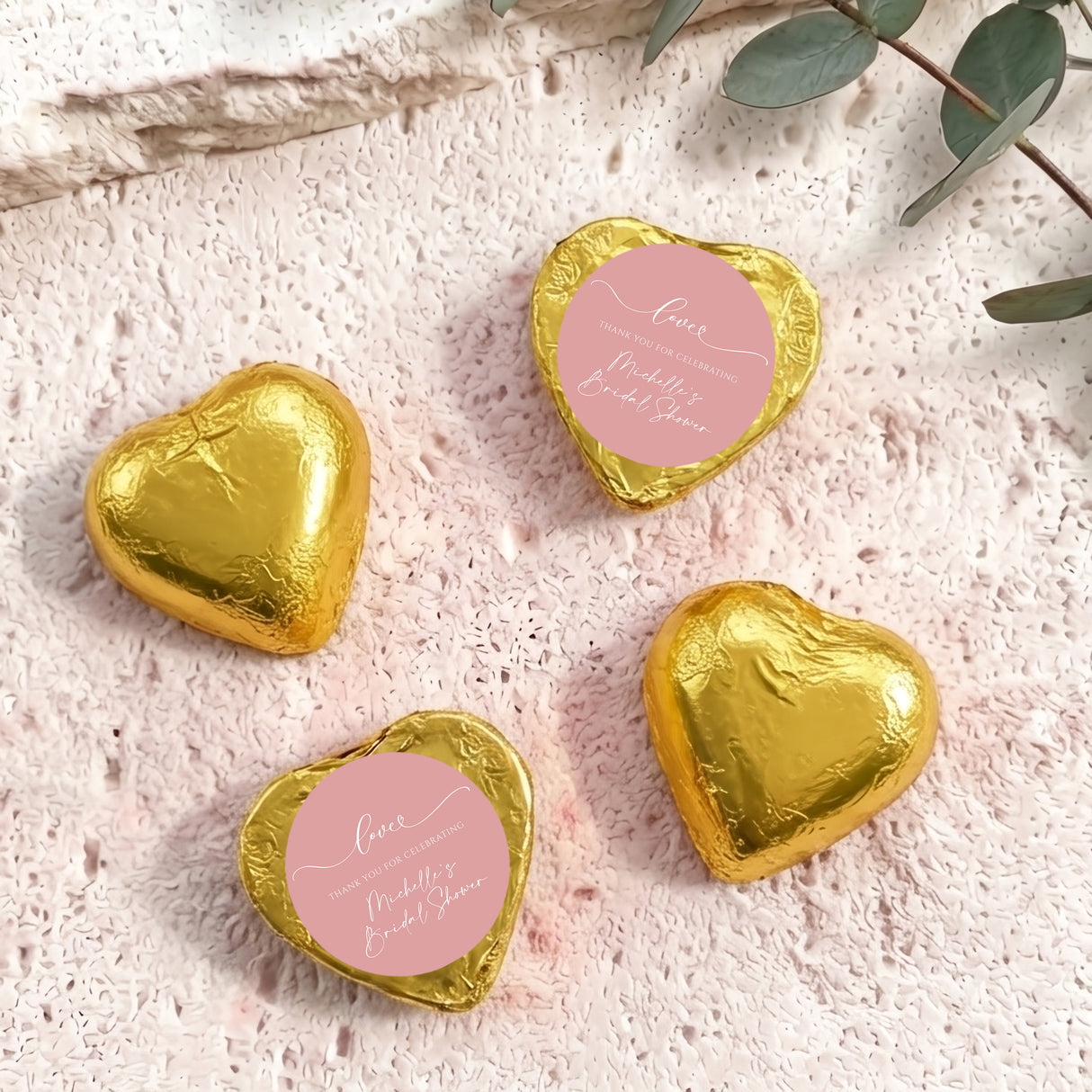 Gold heart-shaped foil-covered chocolates with a round pink label on top