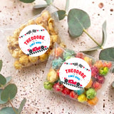 Two personalised popcorn bags with clear pouches of colorful popcorn; labels read THEODORE FAST ONE
