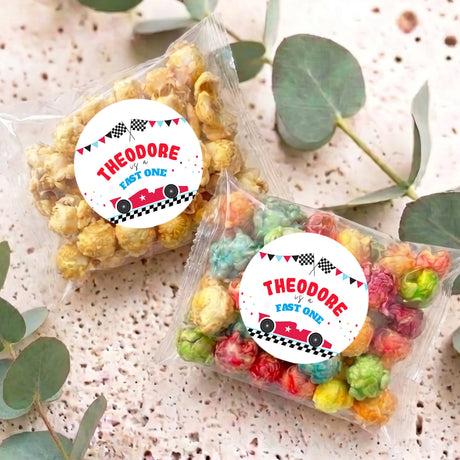 Two personalised popcorn bags with clear pouches of colorful popcorn; labels read THEODORE FAST ONE