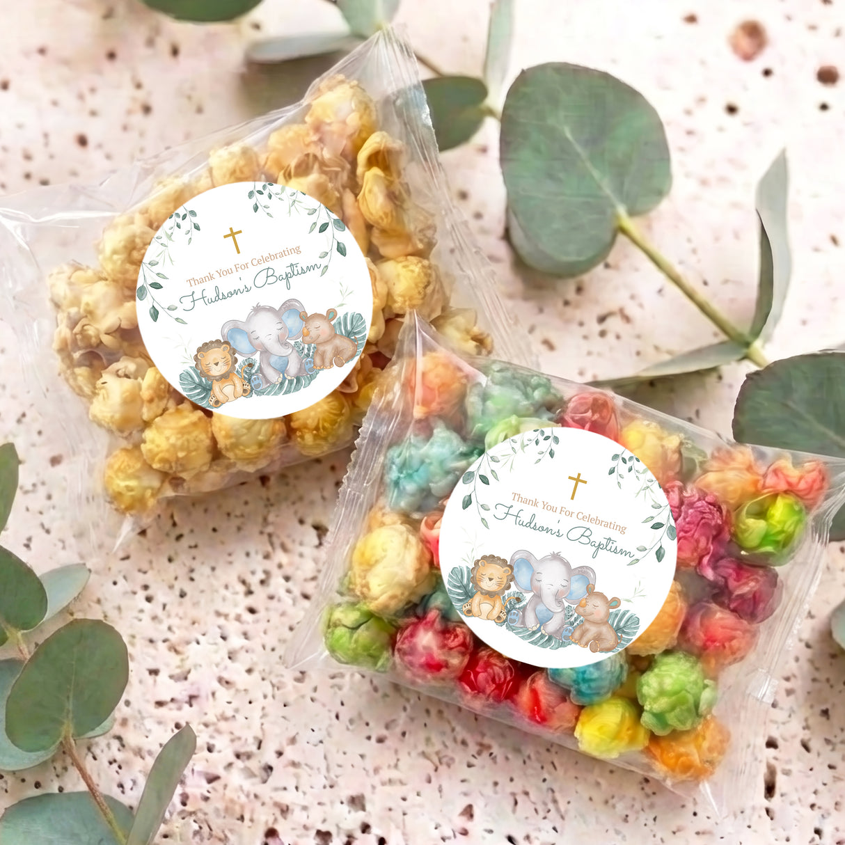 Personalised popcorn bags: two clear bags with round baptism labels and colorful popcorn pieces.