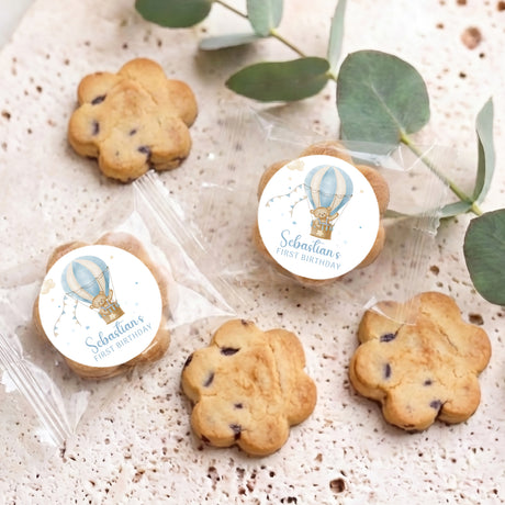 Set of bite-size cookies with blue hot air balloon first birthday labels
