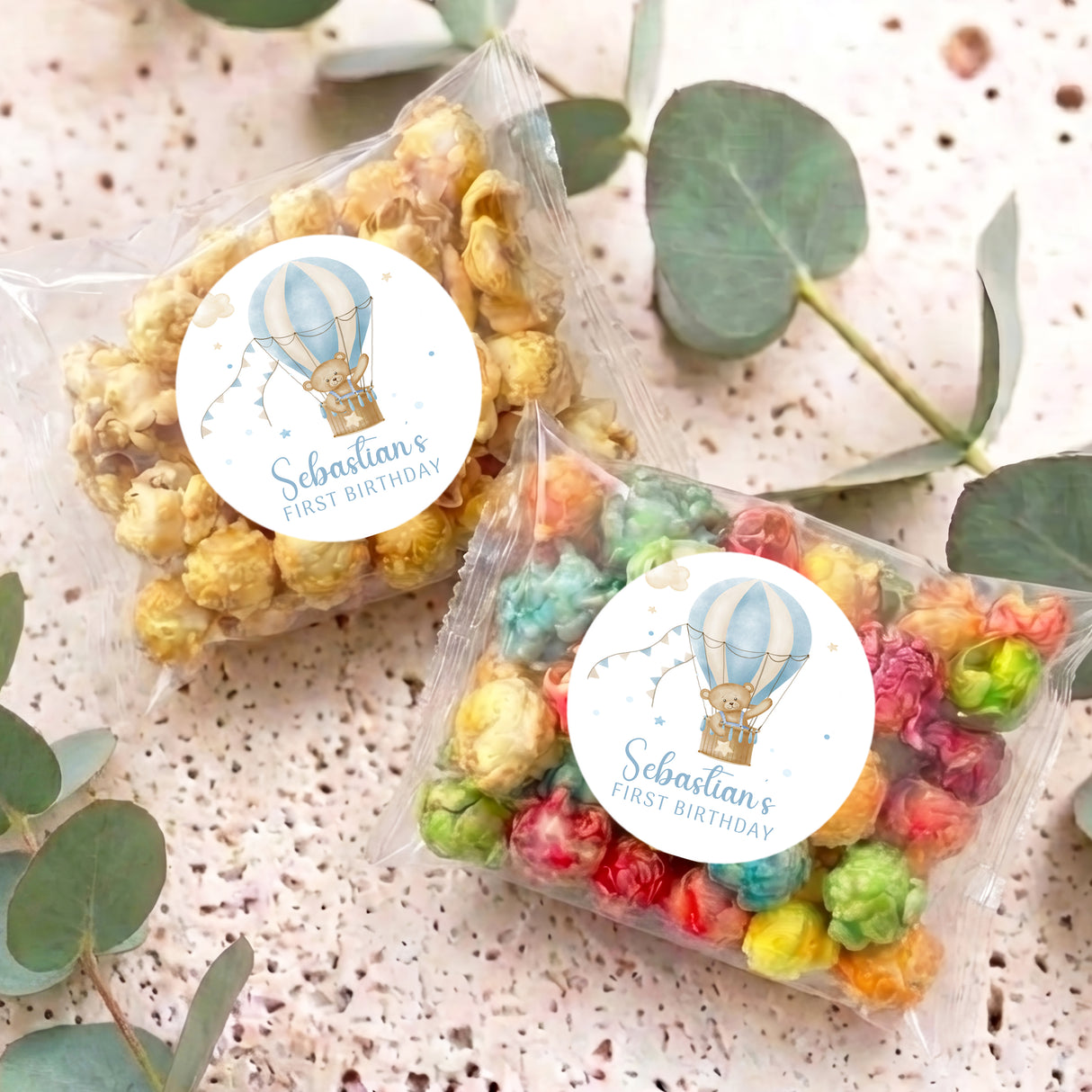Personalised popcorn bags with circular hot air balloon stickers, lying on speckled surface