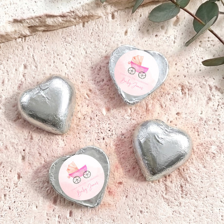 Silver foil-covered heart chocolates with white baby carriage label stickers.