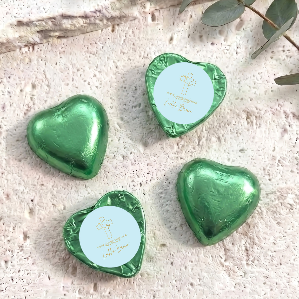 Green foil-covered chocolate hearts with embossed cross and script text on top
