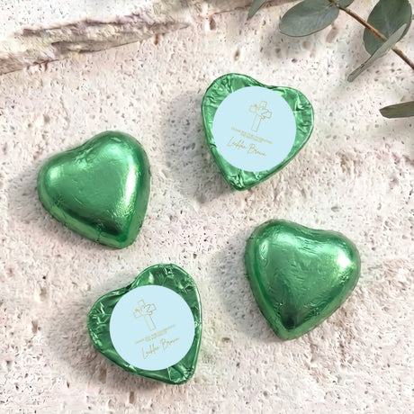 Green foil-covered chocolate hearts with embossed cross and script text on top