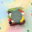 Clear lolly bag with assorted sweets and green thank-you label, front view.