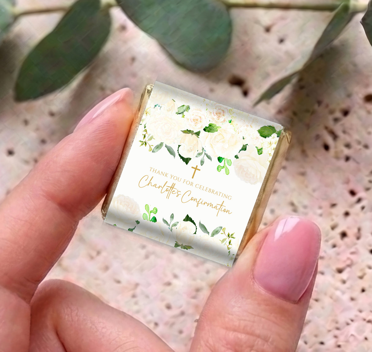 Cream mini chocolate box with floral design and green leaves, held in a hand