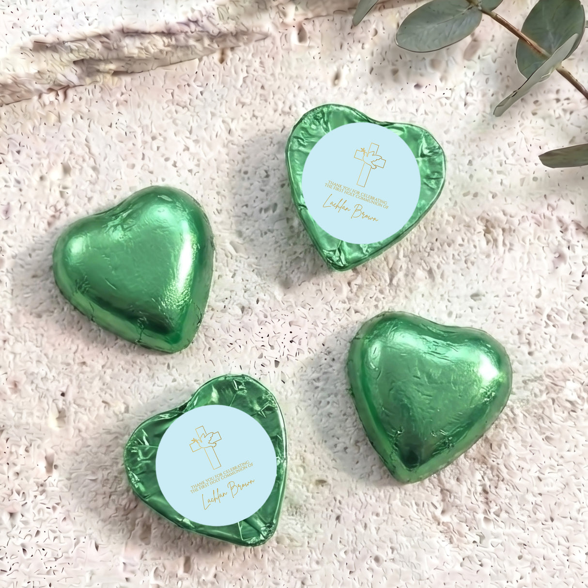 Green foil-covered chocolate hearts with cross and name label on top.