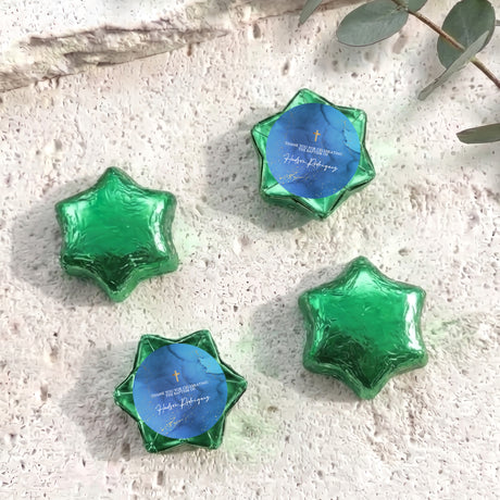Personalised foil-covered chocolate stars in green and blue, with gold cross and text