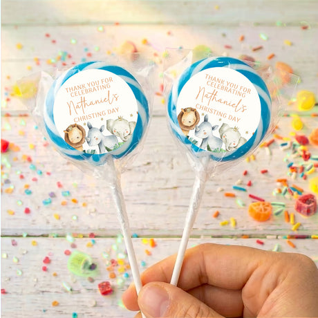 Christening lollipops with clear wrappers and blue watercolor baby animal circle labels, hand-held