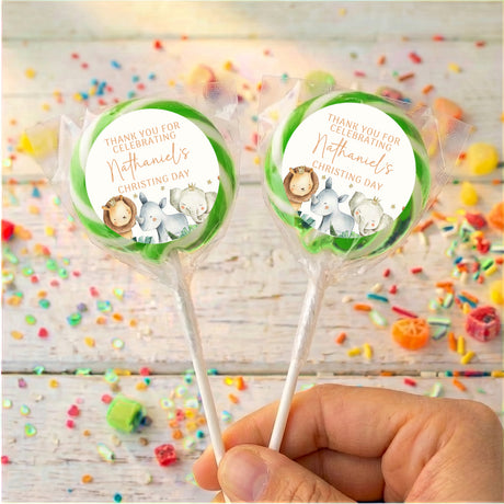 Christening lollipops with clear wrappers and green watercolor baby animal circle labels, hand-held