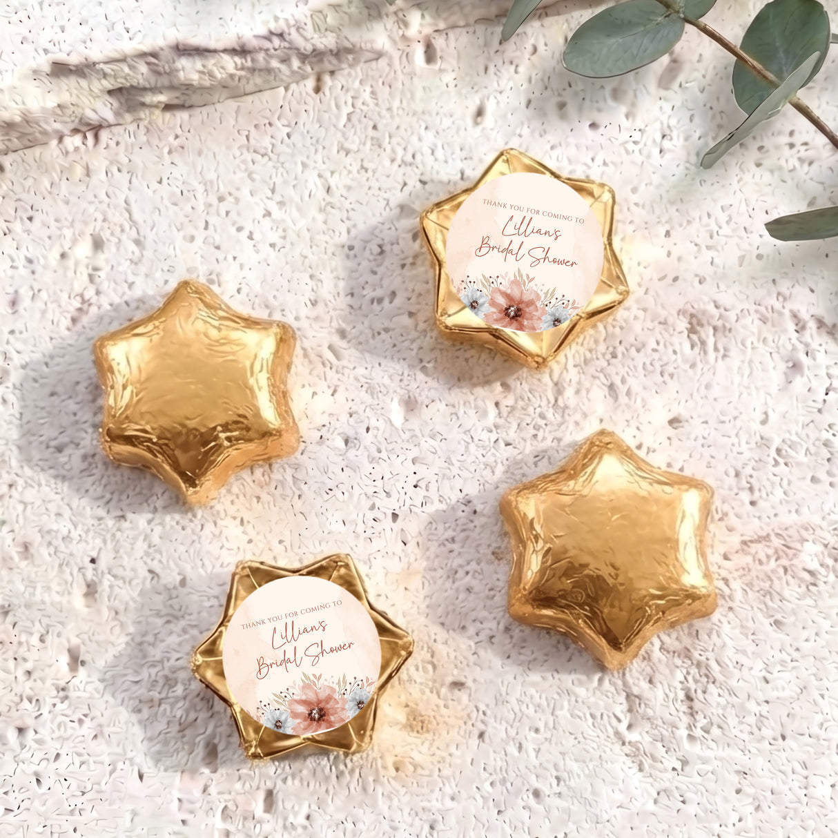 Gold foil-covered chocolate stars with floral bridal shower message labels