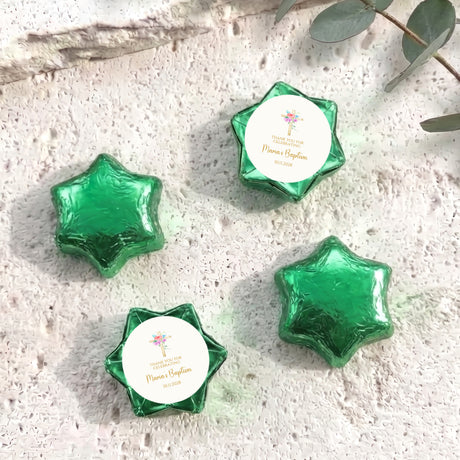 Green foil-covered chocolate stars with white label featuring cross and floral design