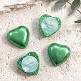 Green foil heart chocolates, one with blue center and gold cross