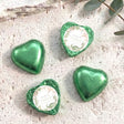 Green foil-covered chocolate hearts, heart-shaped sweets with dinosaur birthday label.
