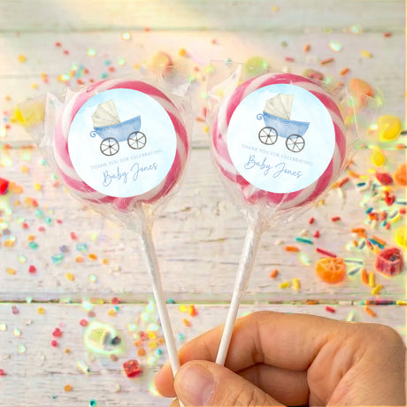 Two lollipops with blue carriage labels in clear wrappers with pink outer ring