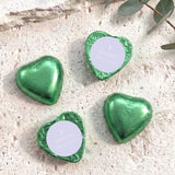 Green foil-covered chocolate hearts with white center card, cross and name text