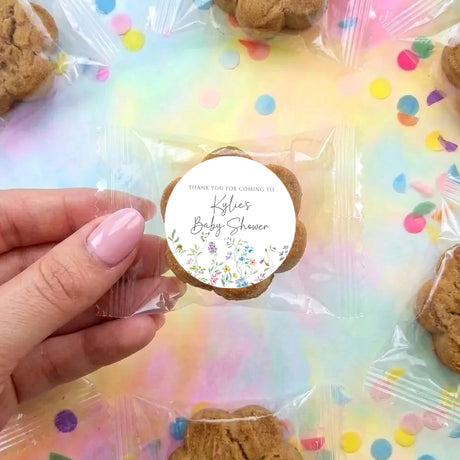 Chocolate chip cookie with round 'Thank you Kylie’s Baby Shower' label, held in hand